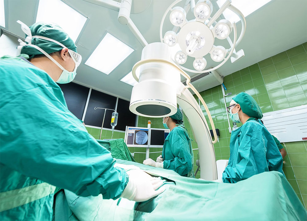 Three surgical team members at work in an operating theatre